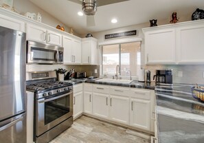 A modern kitchen with white cabinets, stainless steel appliances, a granite countertop, and a window with blinds. - 4 Mi to the Lake! Havasu Home w/ Heated Pool (Lake Havasu City)