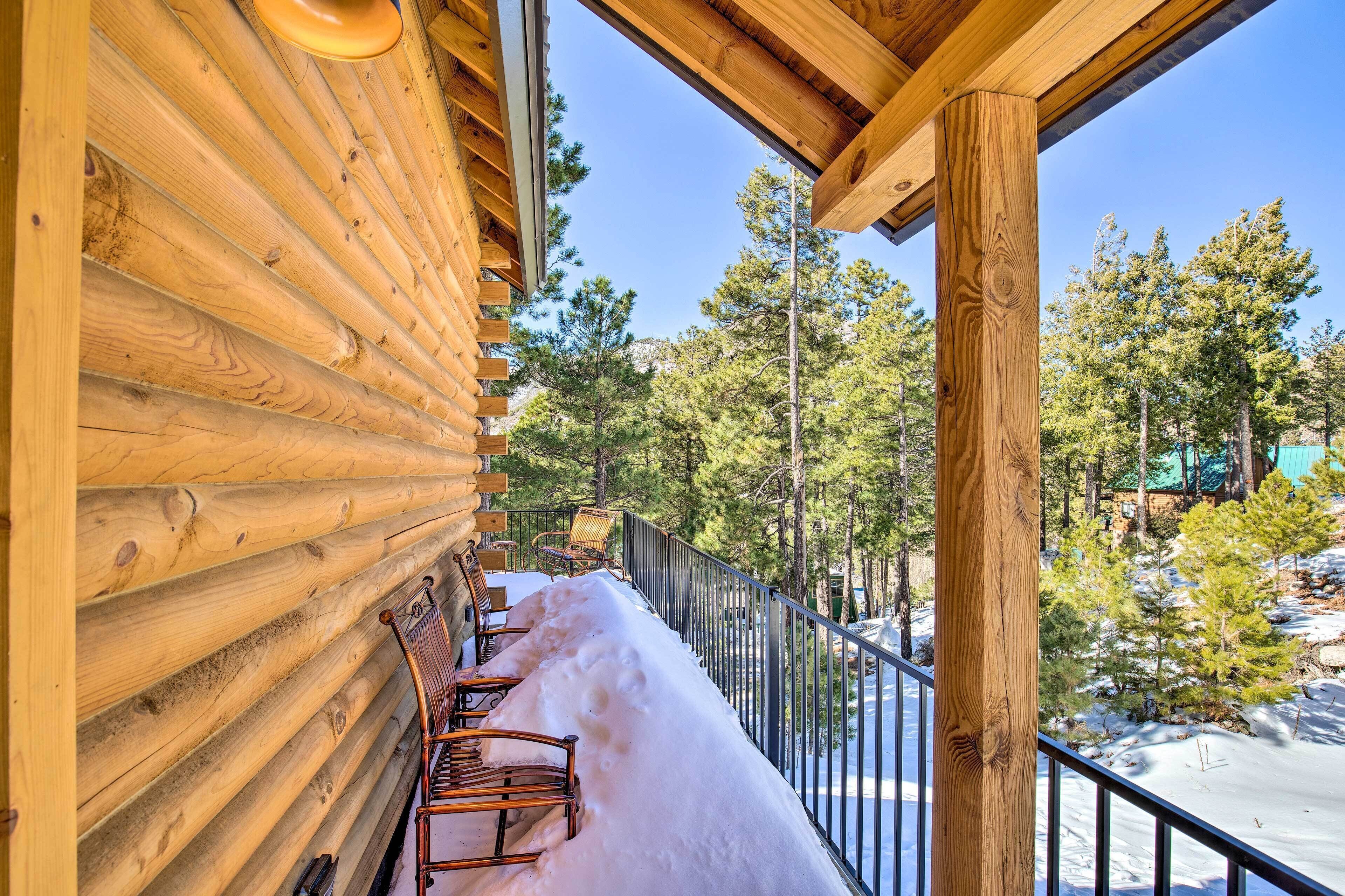 A wooden log cabin with a balcony and a snow-covered ground.