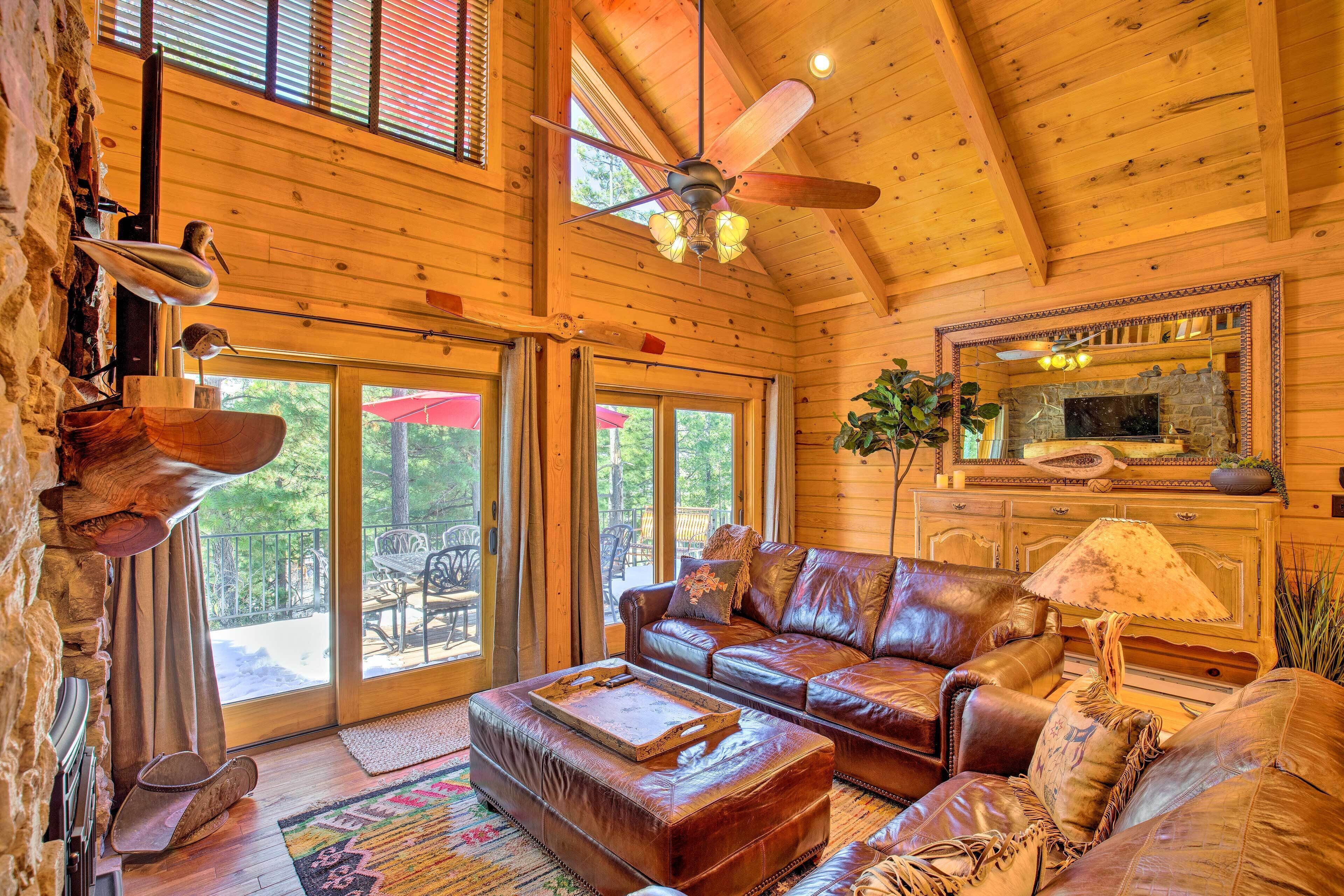 Un intérieur de chalet chaleureux avec un canapé en cuir, un plafond en bois et une cheminée en pierre.
