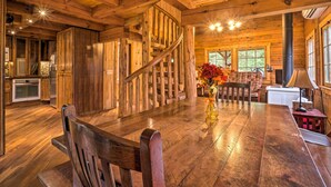 Un interior de madera con una mesa de comedor, sillas, una escalera de caracol y una zona de cocina.