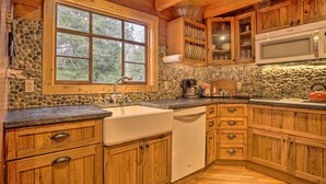 Una cocina con armarios de madera, salpicadero de piedra, un amplio ventanal y un microondas integrado.