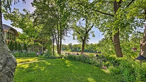 Un exuberante jardín con diversas plantas y árboles, un sendero y un edificio con grandes ventanales.