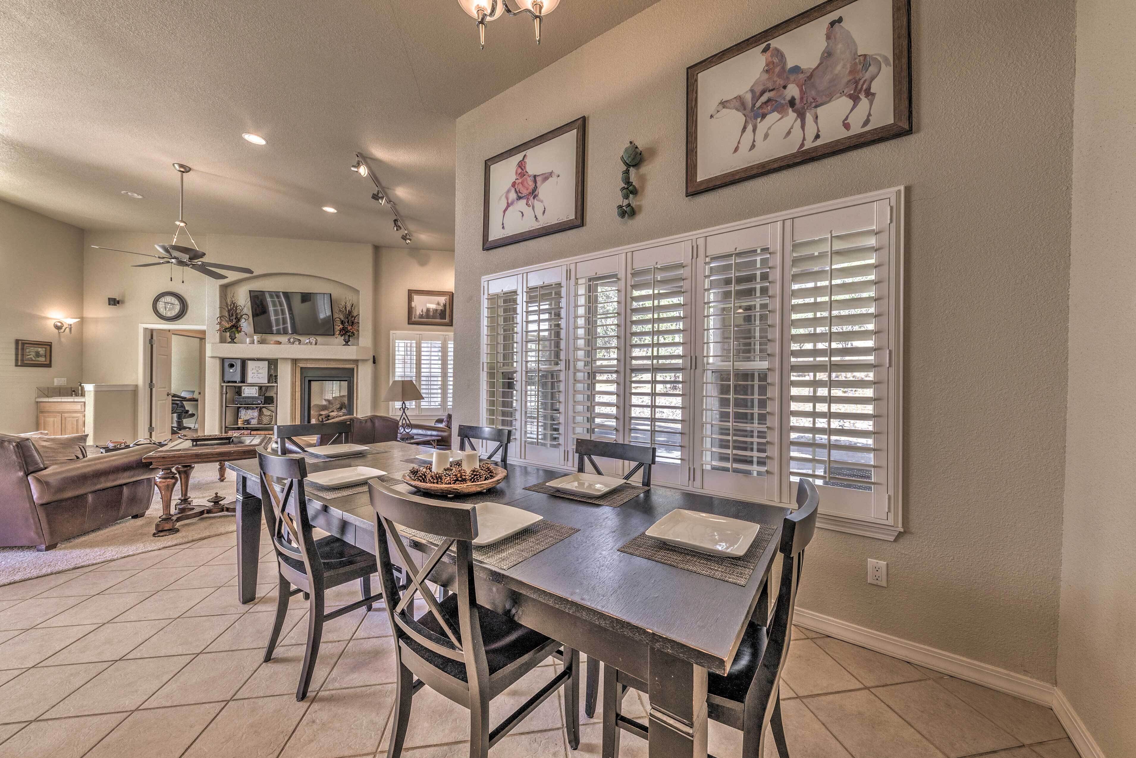 A dining area with a dark wooden table, four chairs, and a TV mounted on the wall.
