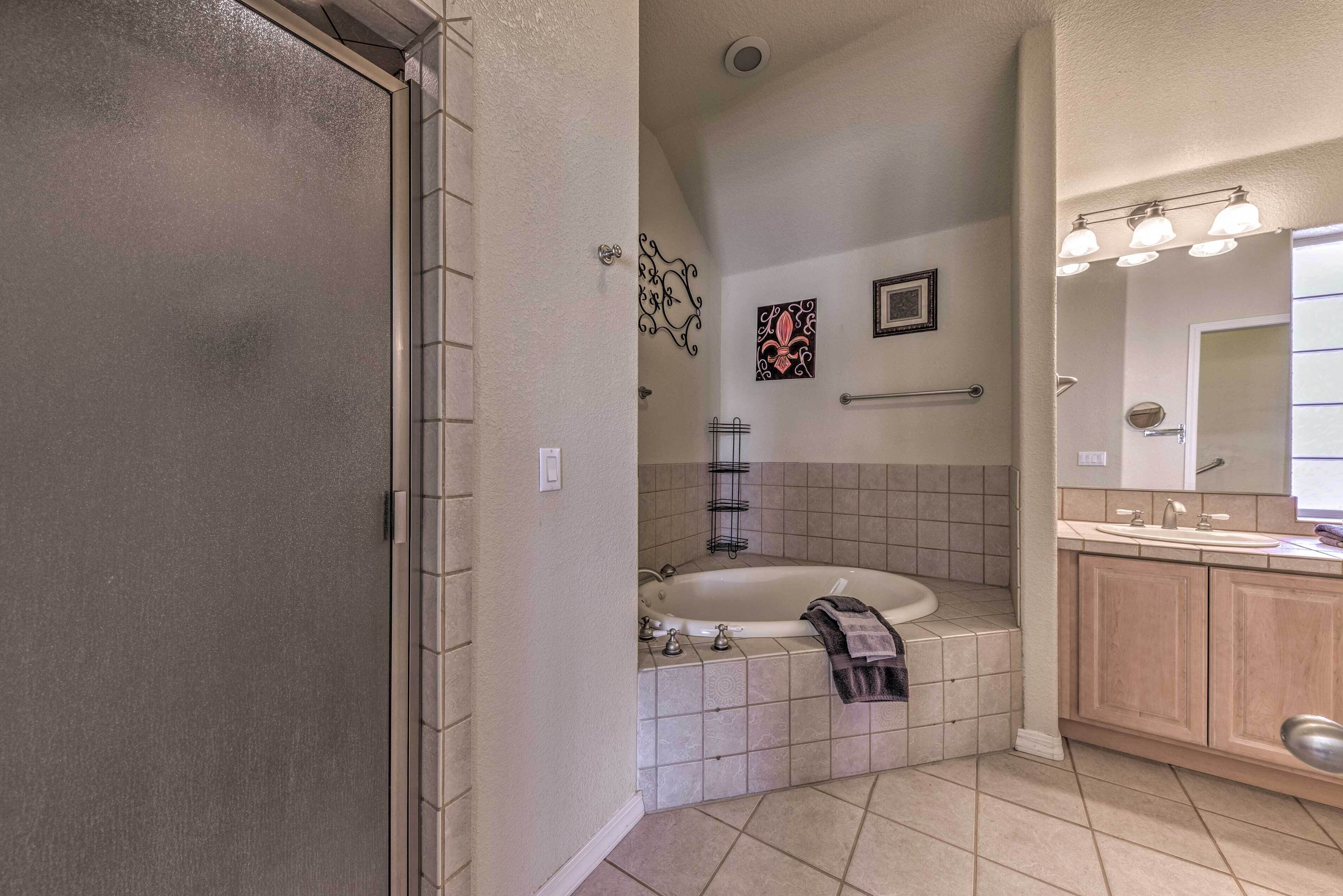 A bathroom with a bathtub, a vanity with a mirror, and a towel rack.