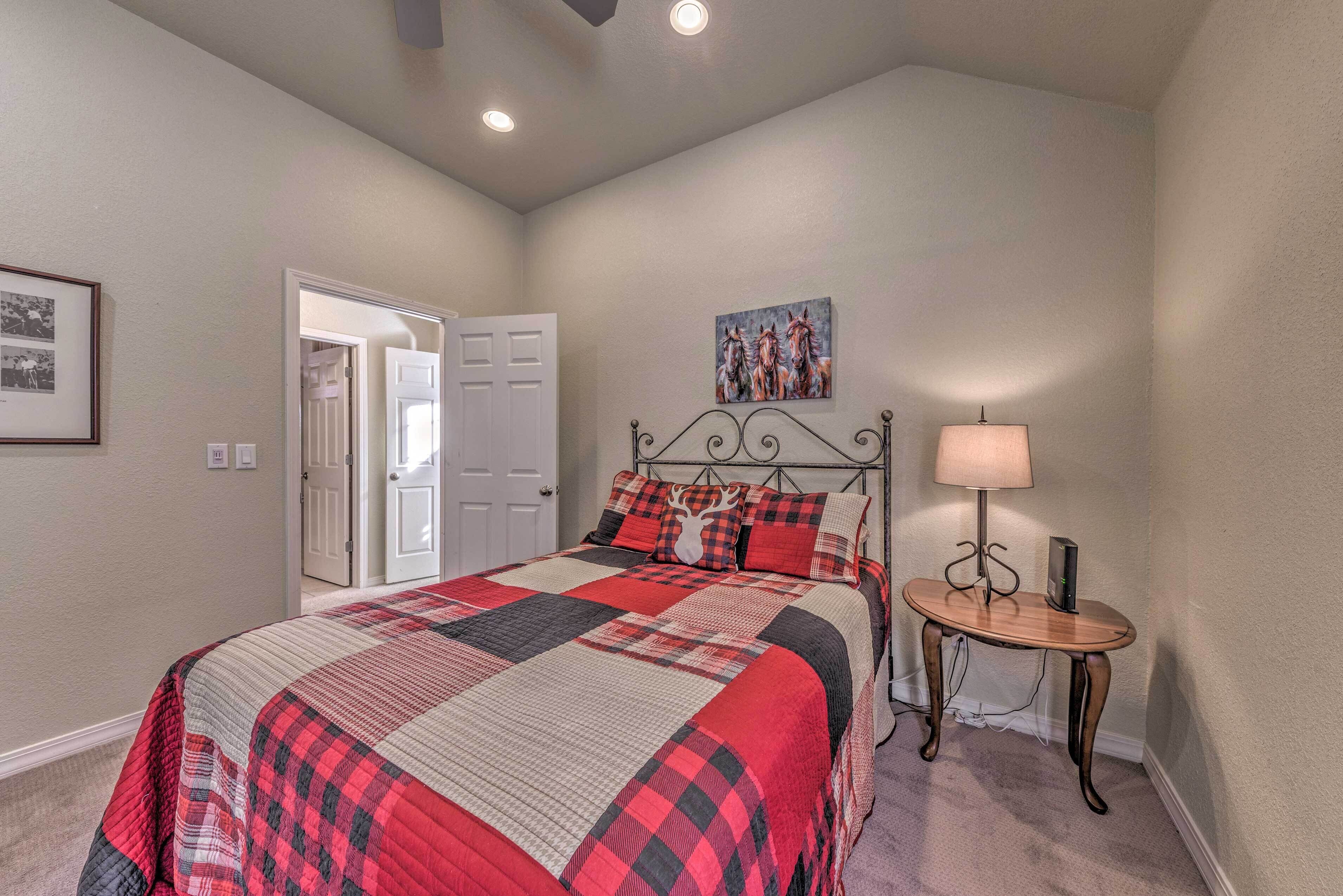 A bedroom with a large bed, a bedside table with a lamp, and a door leading to another room.