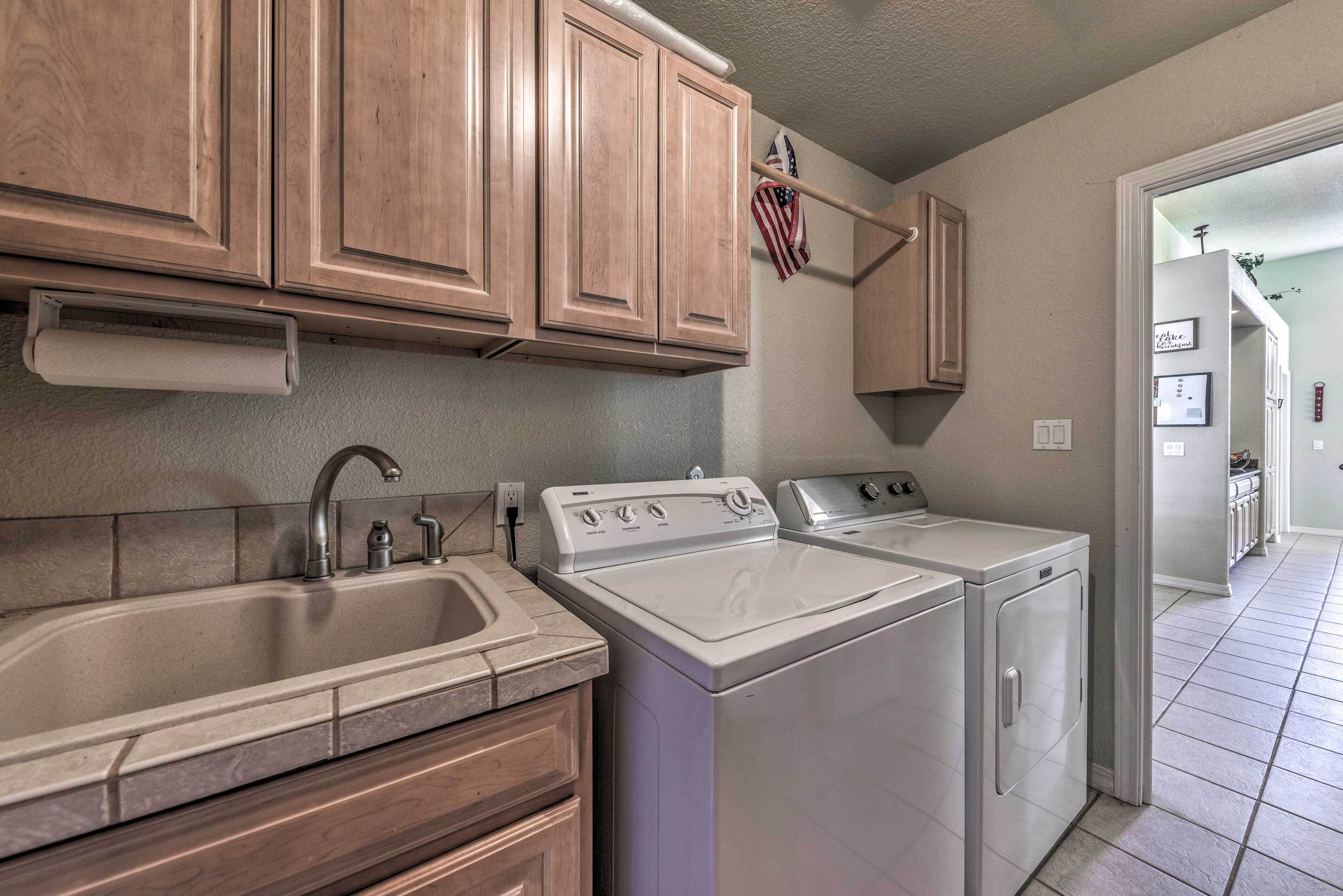 A kitchen with wooden cabinets, a stainless steel sink, and two white appliances.