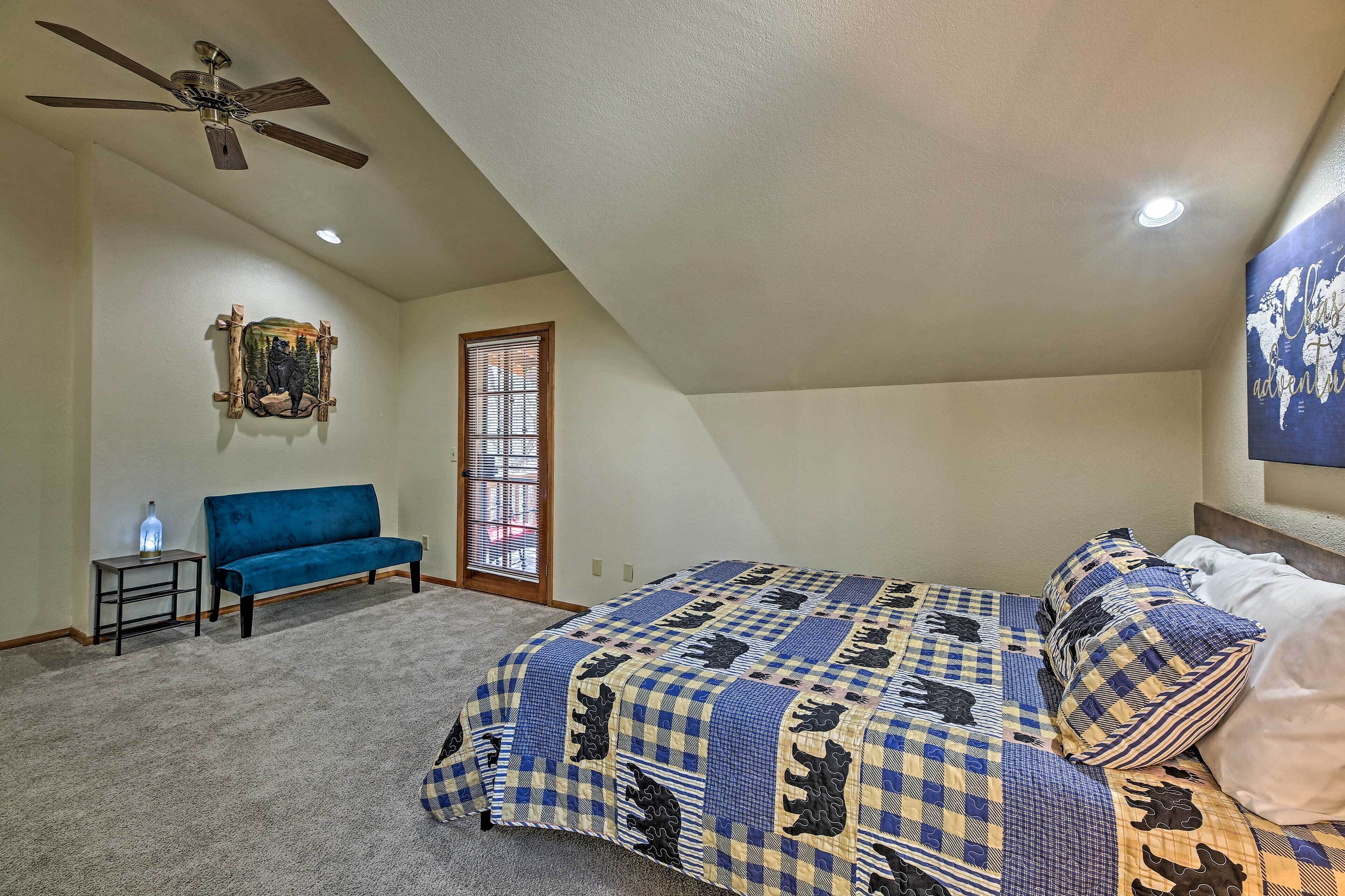 A bedroom with a bed, a blue sofa, a ceiling fan, a window, and a wall-mounted picture.