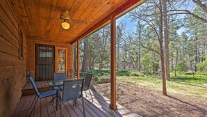 A wooden cabin with a covered porch, a table with chairs, and a view of a forest. - 2 Decks & Game Room: Expansive Family Cabin (Pinetop)
