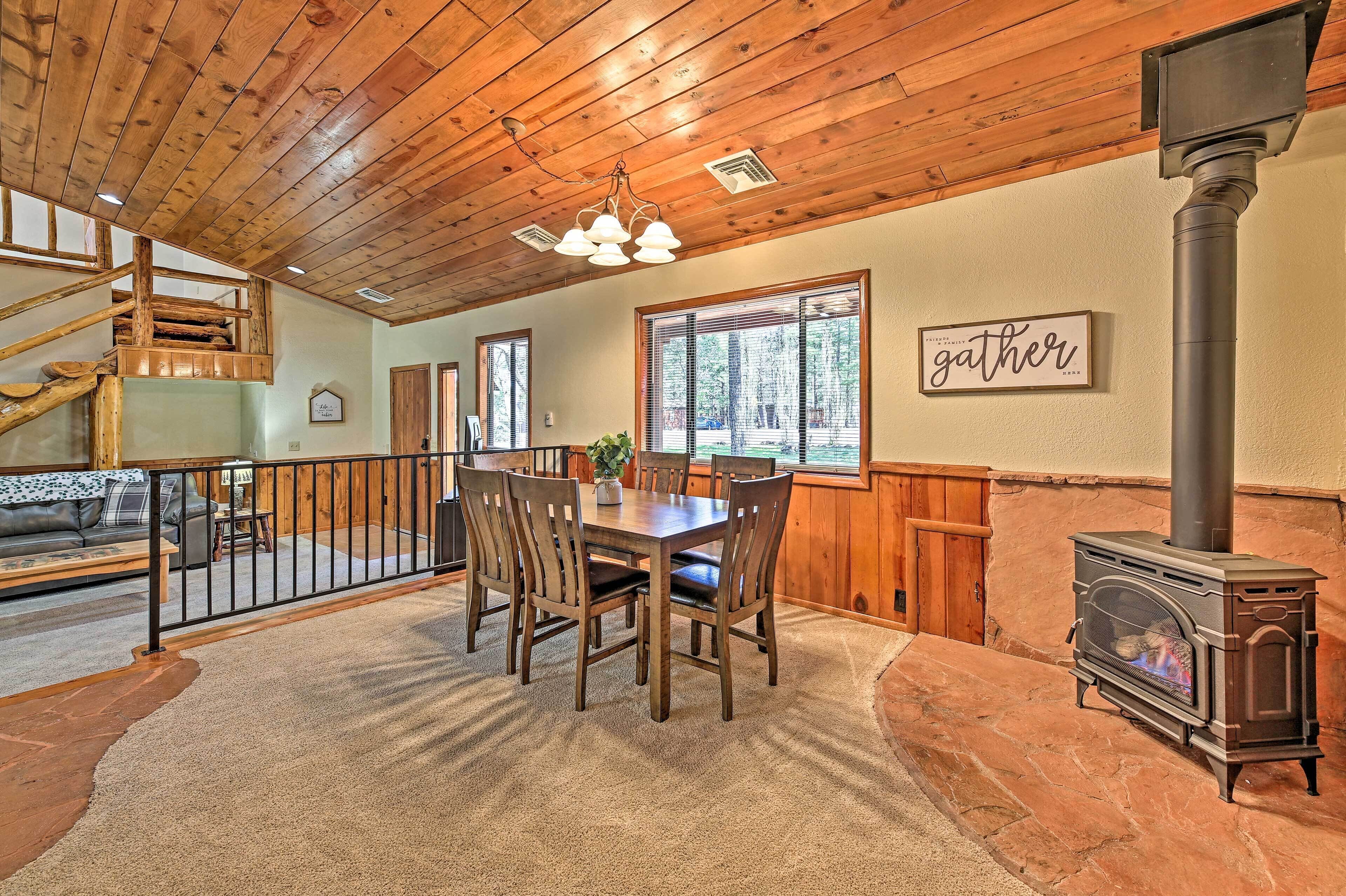 A wooden interior with a dining table, chairs, a fireplace, and a staircase.