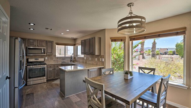 A modern kitchen with a central island, built-in appliances, and a large window offering a view of the outdoors.