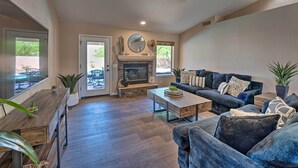 A spacious living room with a fireplace, comfortable seating, and a view through glass doors.
