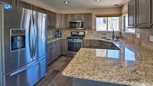 A modern kitchen with stainless steel appliances, granite countertops, and wooden cabinets.