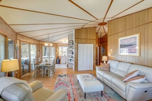 A spacious living room with a large white sofa, a coffee table, and a dining area with a table and chairs. - Mountaintop Mars Hill Cabin w/ Wraparound Deck! (Mars Hill)