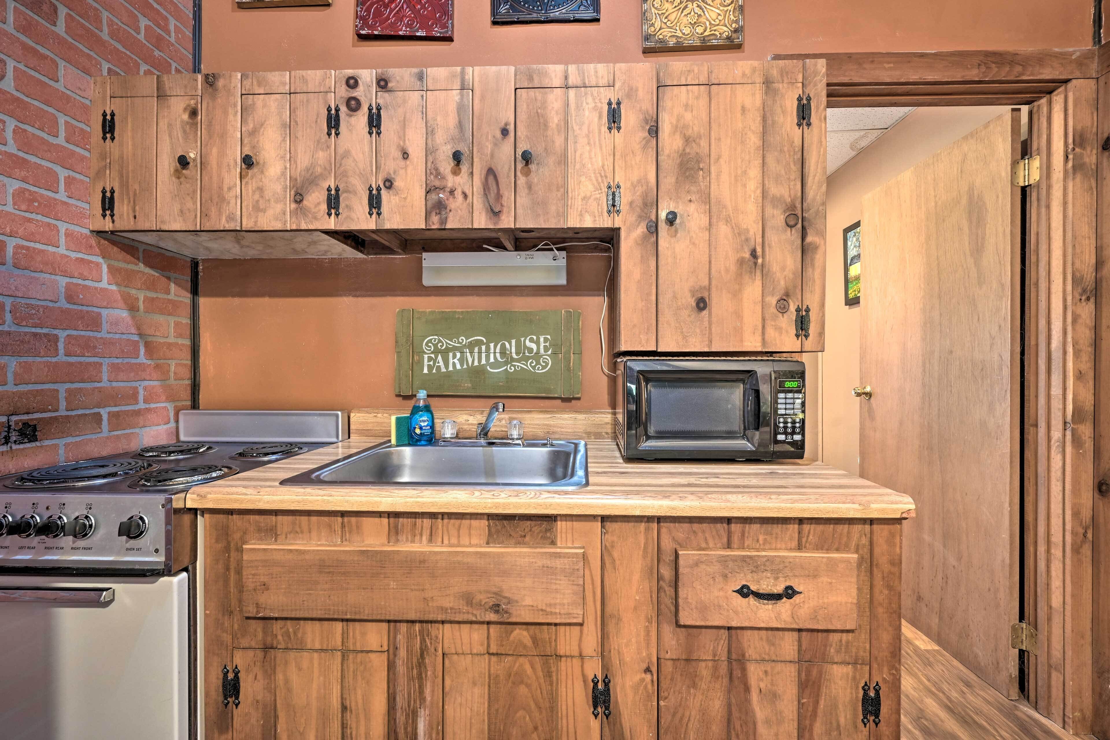 A kitchen with wooden cabinets, a stove, a microwave, and a sink.