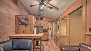 A cozy room with a wooden ceiling fan, a brick wall, a wooden bench, and a kitchenette area. - 1 Mi to Raystown Lake: Bill Pickett Ranch Apt (Huntingdon)