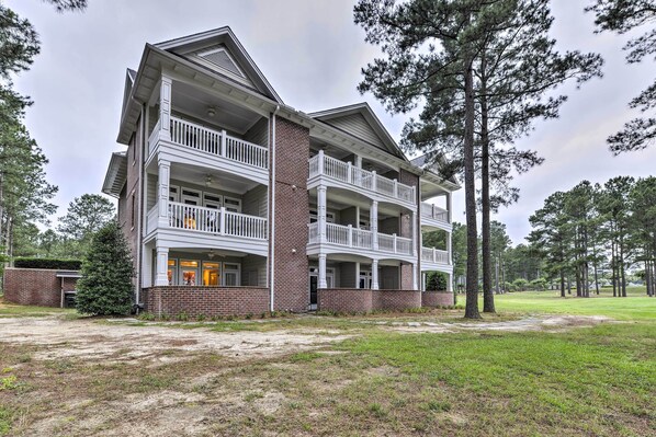 A multi-story building with a brick facade, multiple balconies, and a covered front porch.