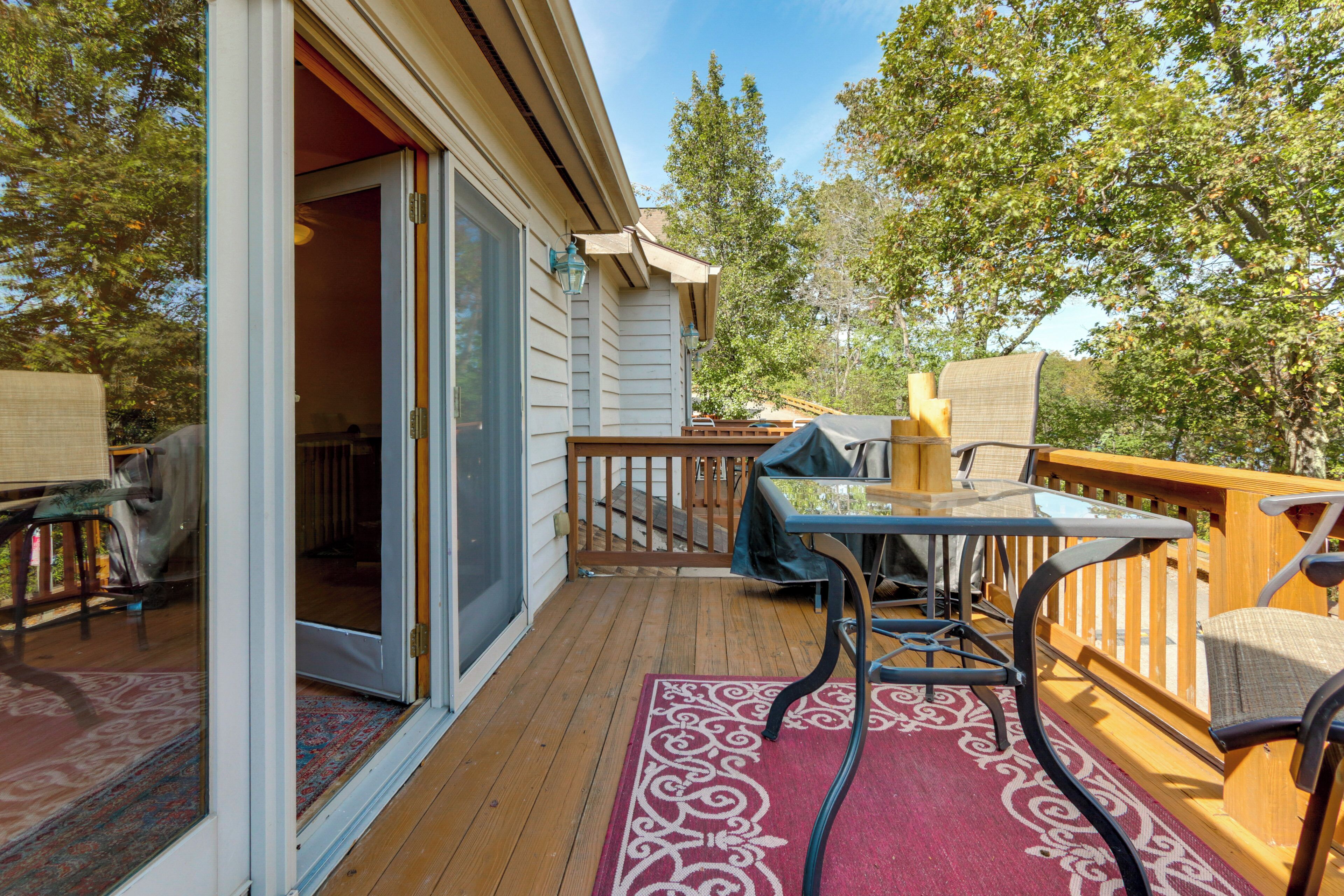 A wooden deck with a table and chairs, a covered area, and a sliding glass door leading to an interior space.