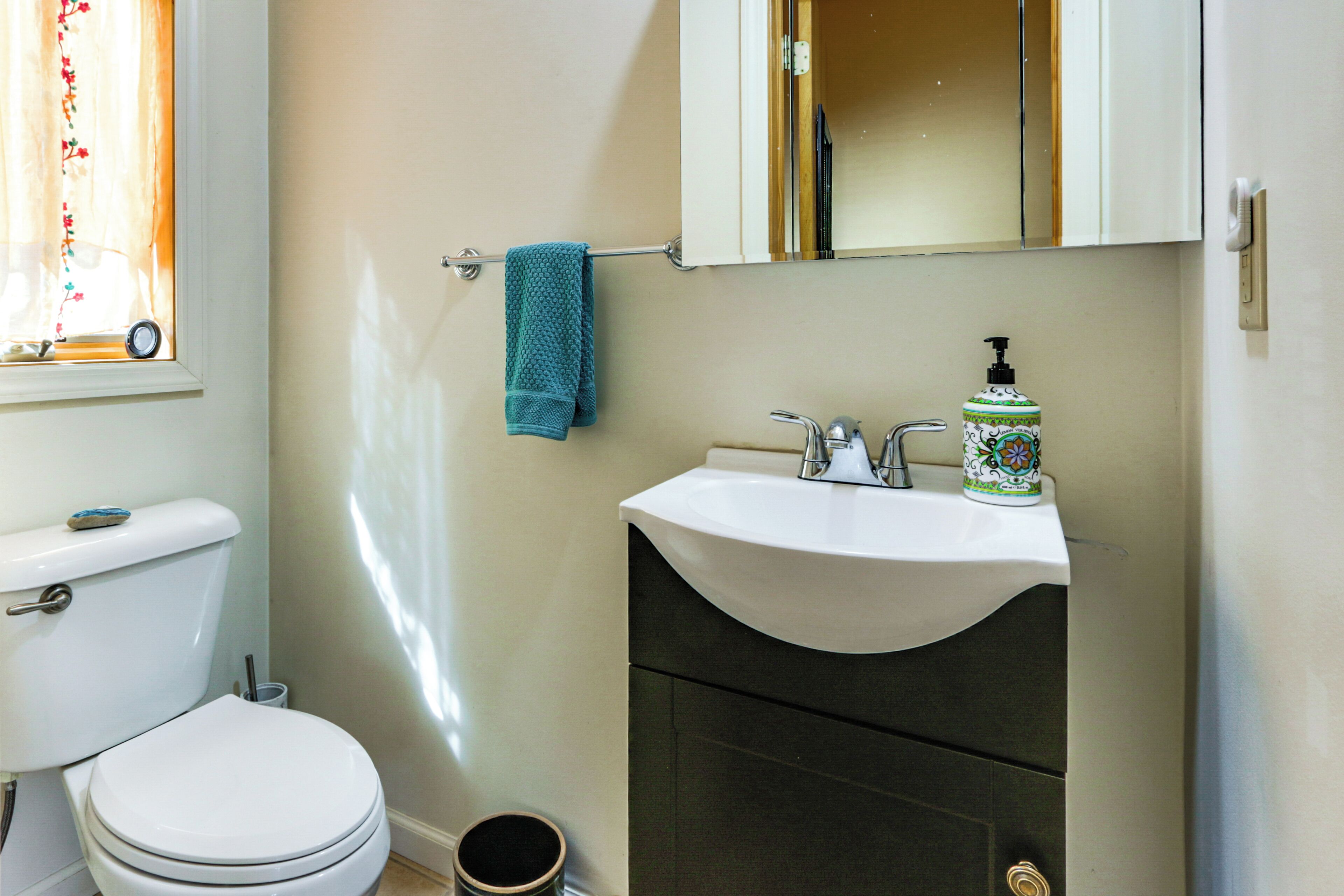 A bathroom with a toilet, sink, and mirror.