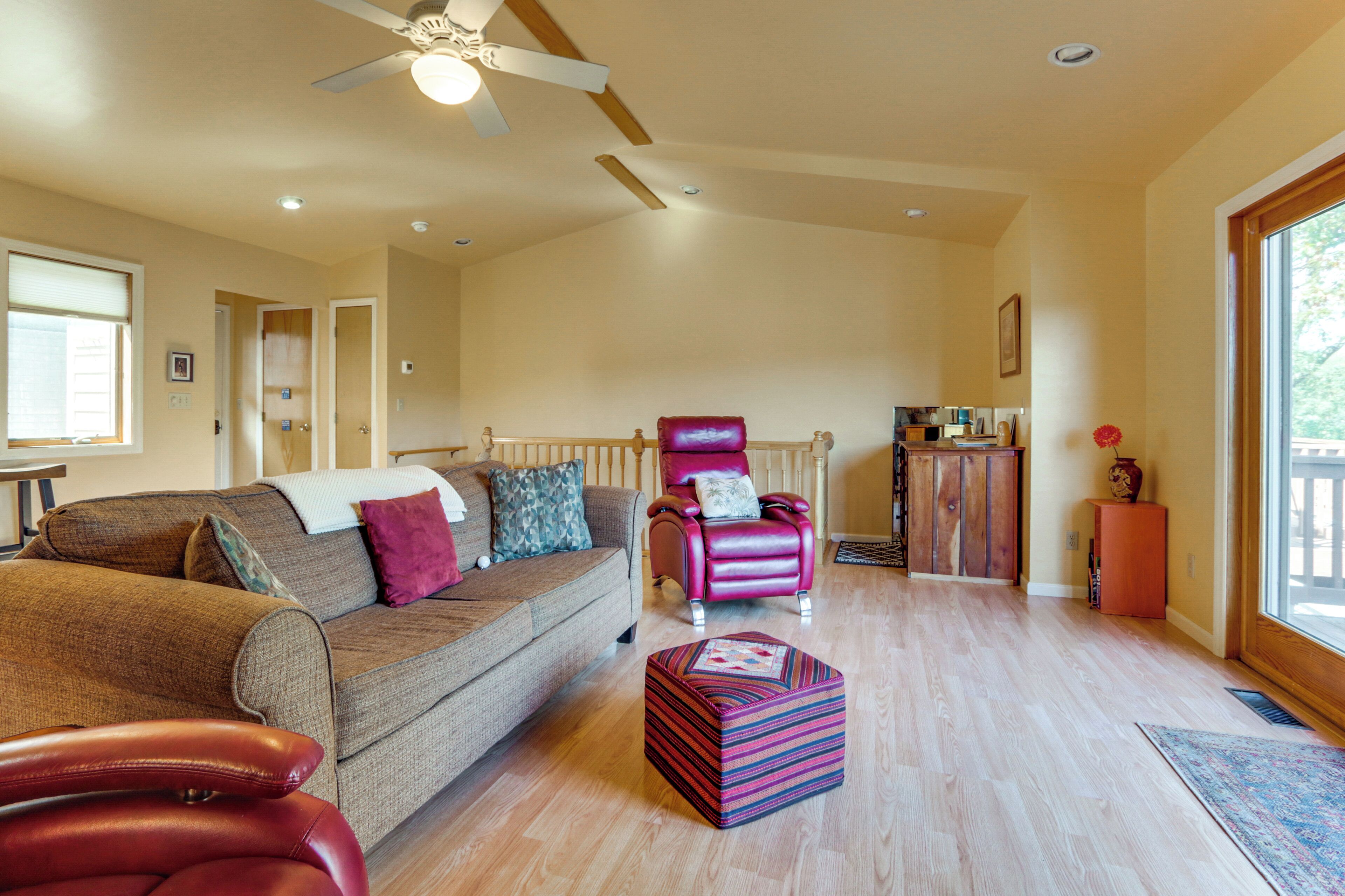 A spacious living room with a brown sofa, a red chair, and a wooden cabinet.