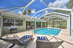 A covered outdoor swimming pool with lounge chairs, a grill, and a patio area with chairs and tables. - Dog-friendly Escape w/ Dock & Kayaks in Cape Coral (Cape Coral)