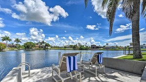A poolside area with lounge chairs and a view of a lake and surrounding buildings. - Dog-friendly Escape w/ Dock & Kayaks in Cape Coral (Cape Coral)