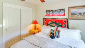 A bedroom with a bed, a nightstand with a lamp, a door, and a wall with a painting. - Walk to Main St! Ennis Townhome w/ Balcony (Ennis)