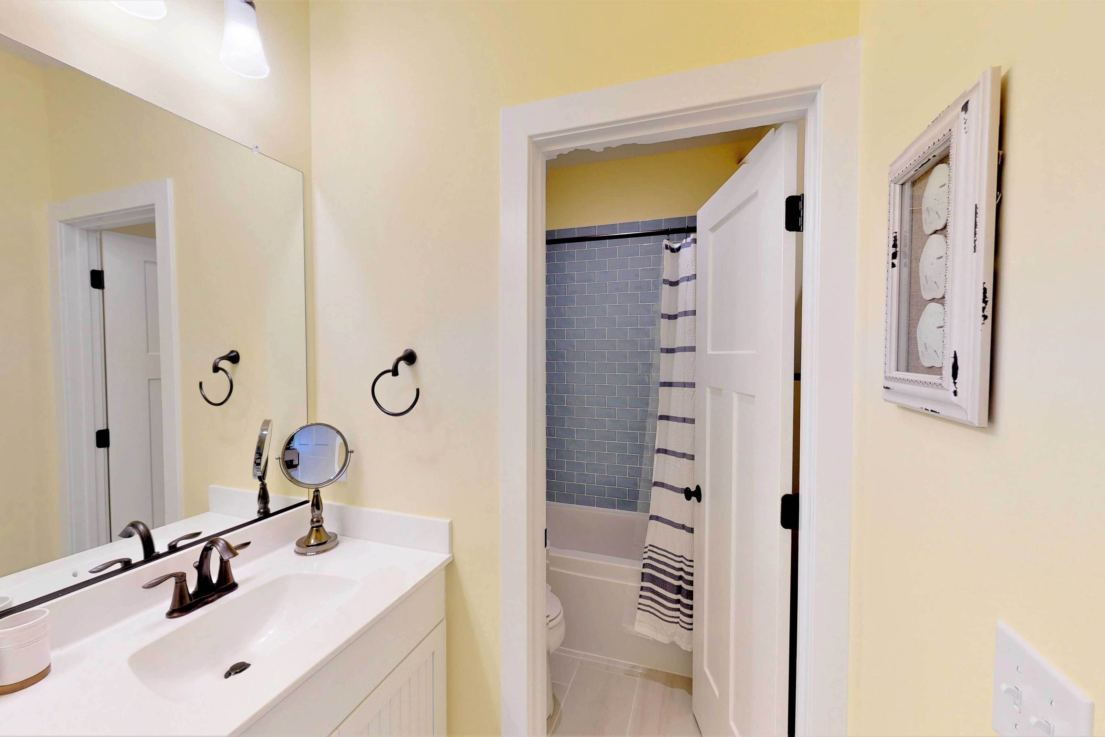 A bathroom with a white sink, a mirror, and a shower area with a blue tiled wall.