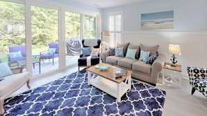 A spacious living room with a large window, a sofa, a coffee table, and a patterned rug. - 2 Mi to Bethany Beach: Family-friendly Home! (Ocean View)
