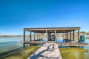 A wooden pier leading to a covered structure with benches and a small boat. - Family Home w/ Boat Dock, Fire Pit + Balcony (Trinity)