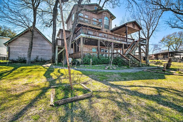 A large wooden house with multiple levels, a prominent staircase, and a deck. - Family Home w/ Boat Dock, Fire Pit + Balcony (Trinity)