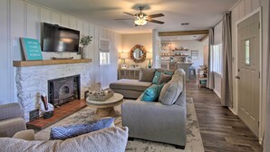 A living room with a fireplace, sofa, and television. - Dock & Grand Lake Access! Idyllic Afton Getaway (Afton)