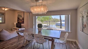 A dining area with a table, chairs, a chandelier, a television, and artwork on the walls. - Dock & Grand Lake Access! Idyllic Afton Getaway (Afton)
