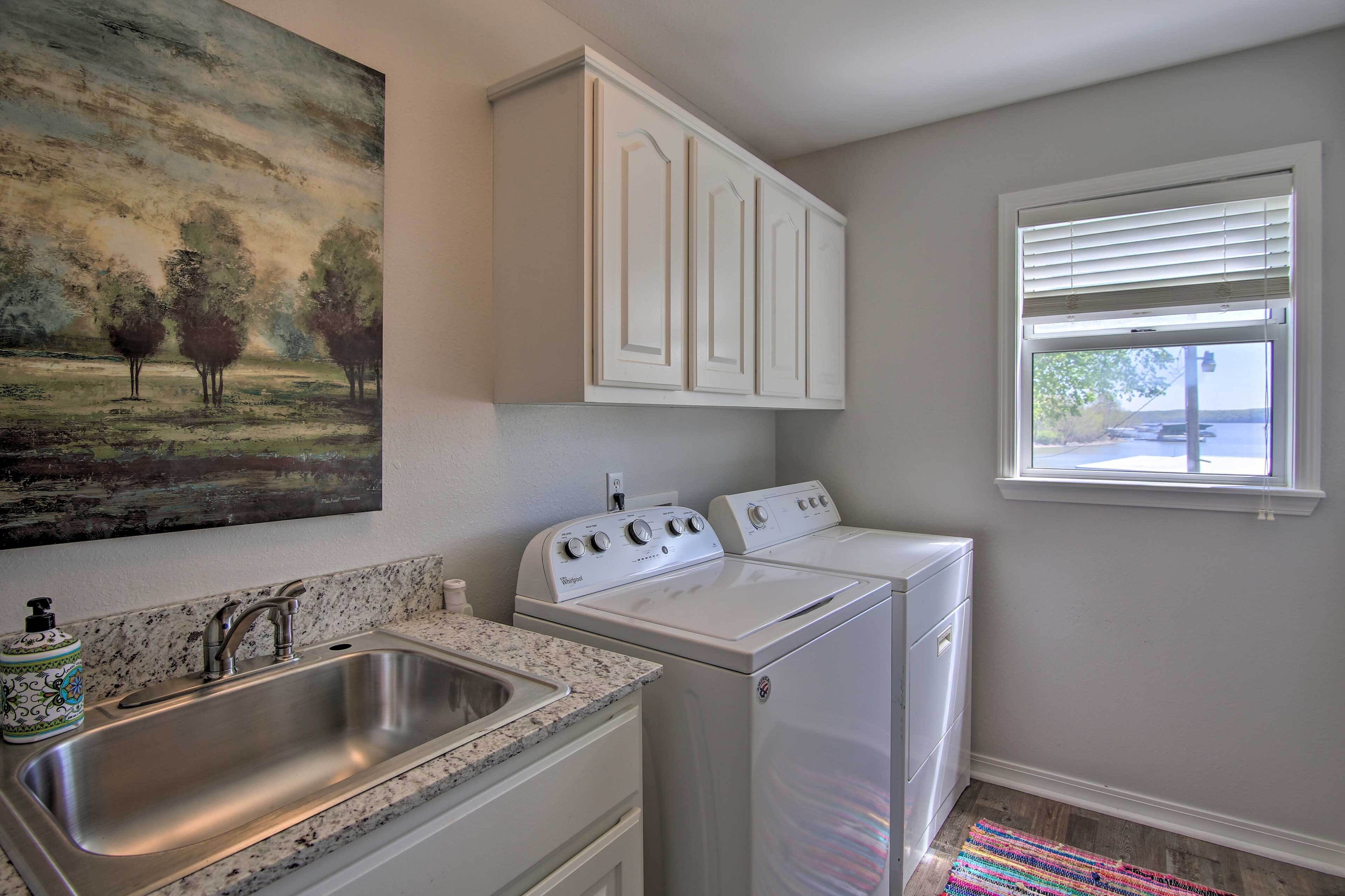 A laundry room with a sink, two washers, and a painting on the wall.