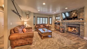 A living room with a fireplace, leather sofas, a coffee table, and a mounted deer head. - 4 Mi to Woodland Lake: 2-story Home w/ Grill (Pinetop)