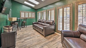 A living room with a brown leather sofa, a wooden cabinet, and a table with chairs. - 4 Mi to Woodland Lake: 2-story Home w/ Grill (Pinetop)