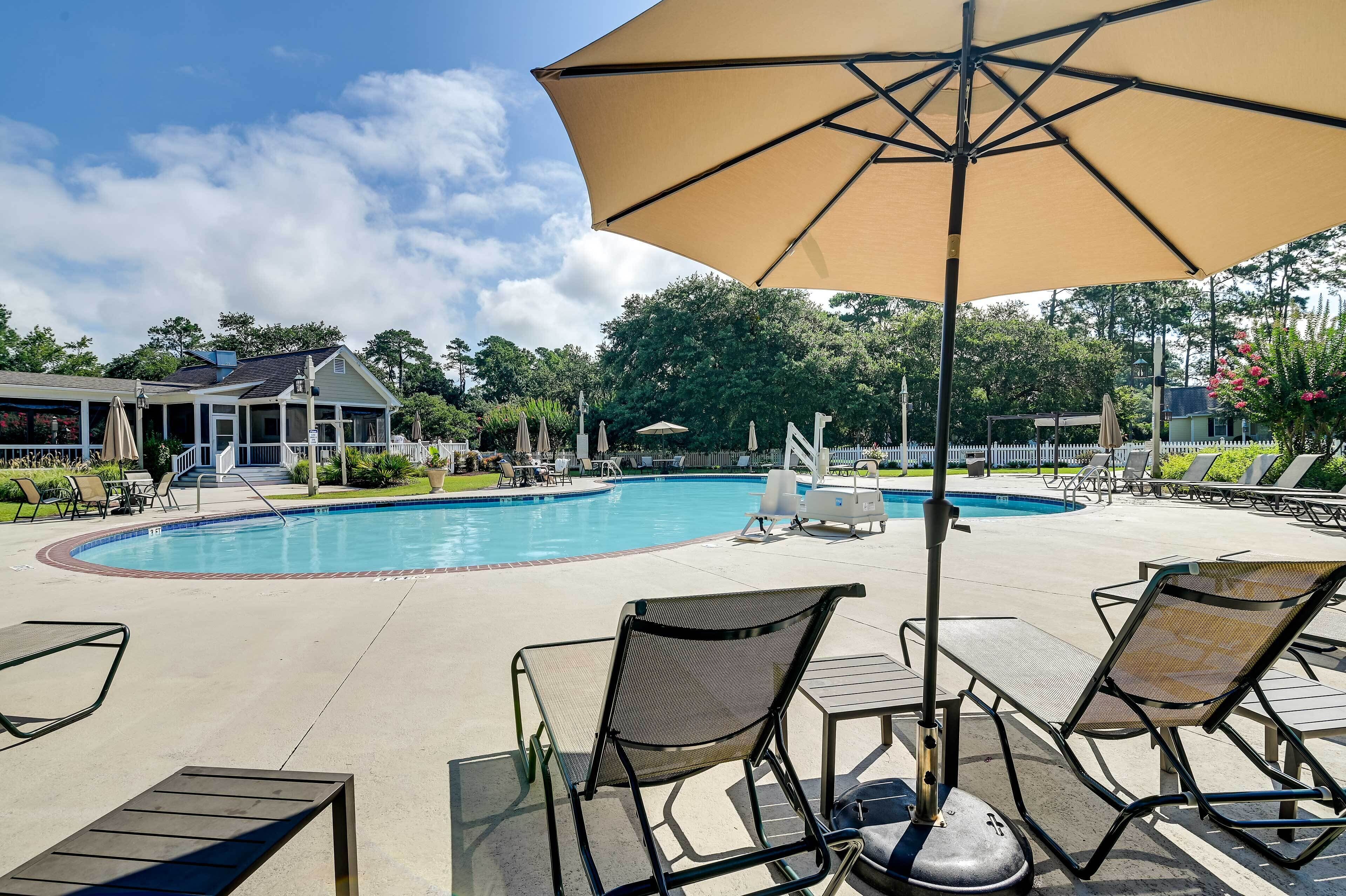 A poolside area with lounge chairs, umbrellas, and a pool.