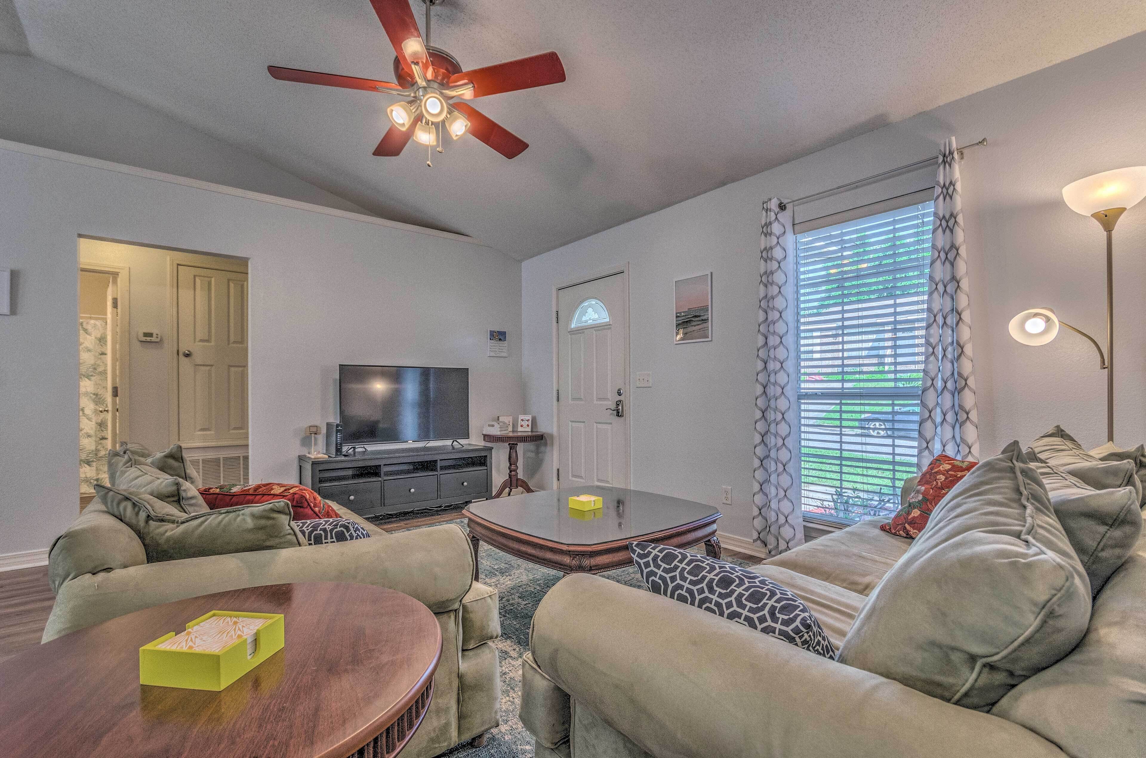 A living room with a sofa, coffee table, TV, and ceiling fan.