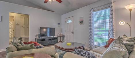 A living room with a sofa, coffee table, TV, and ceiling fan.