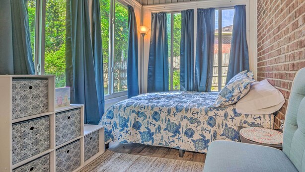 A bedroom with a bed, a nightstand, a lamp, and a window with curtains. - Home 10 Mi to Downtown Pensacola: Pets Welcome! (Pensacola)