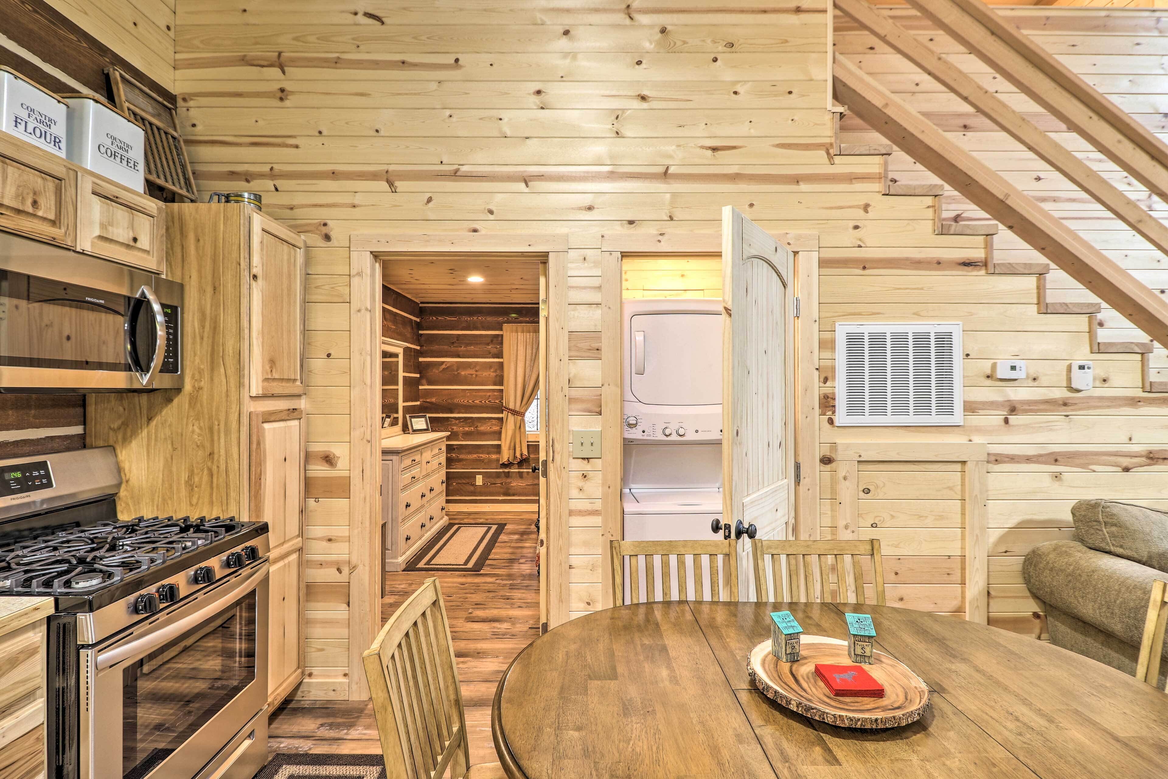Interior de una cabaña de madera con una zona de cocina que incluye estufa, microondas y armarios.