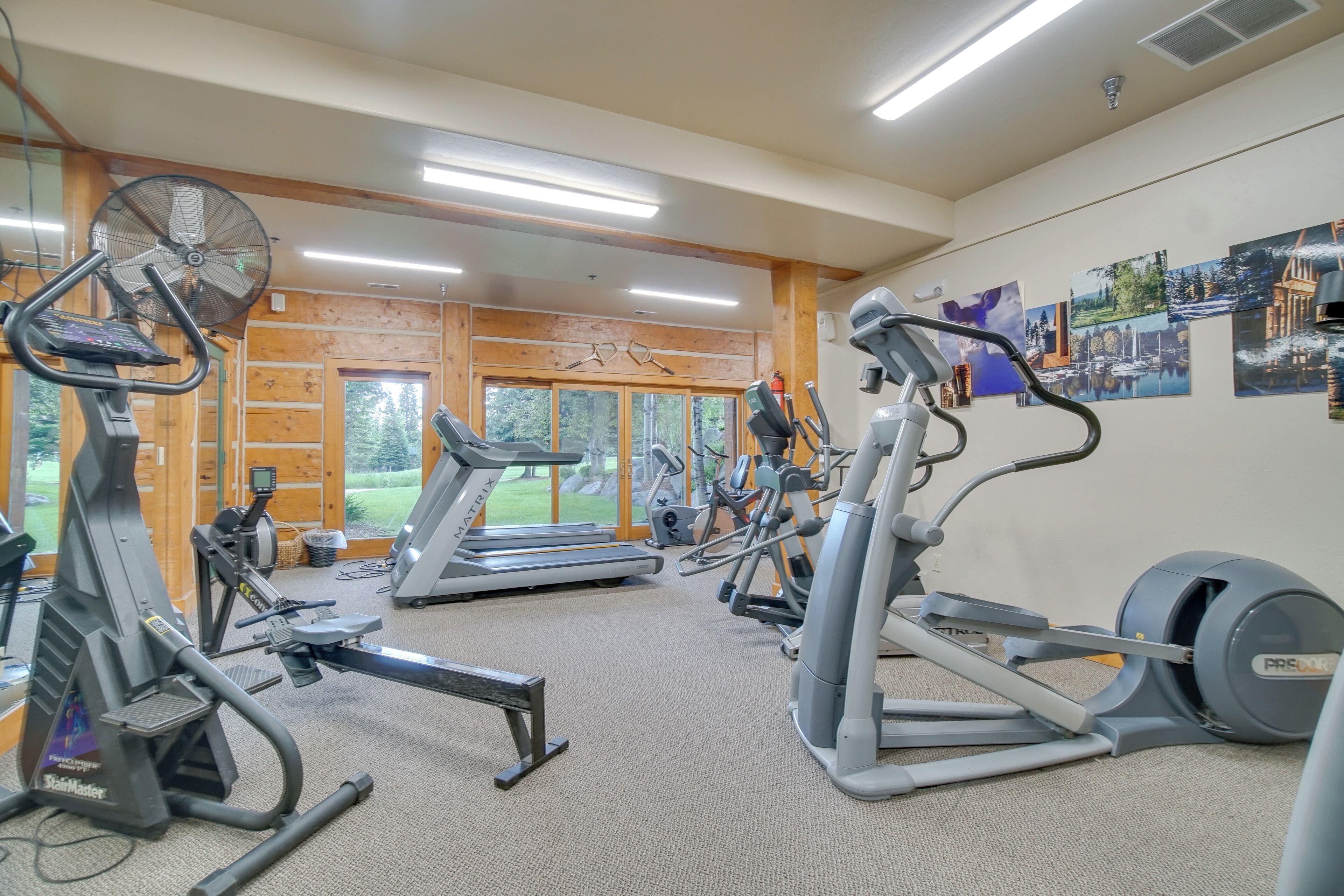 Ein Fitnessstudio mit unterschiedlichen Trainingsgeräten, großen Fenstern und Blick ins Freie.