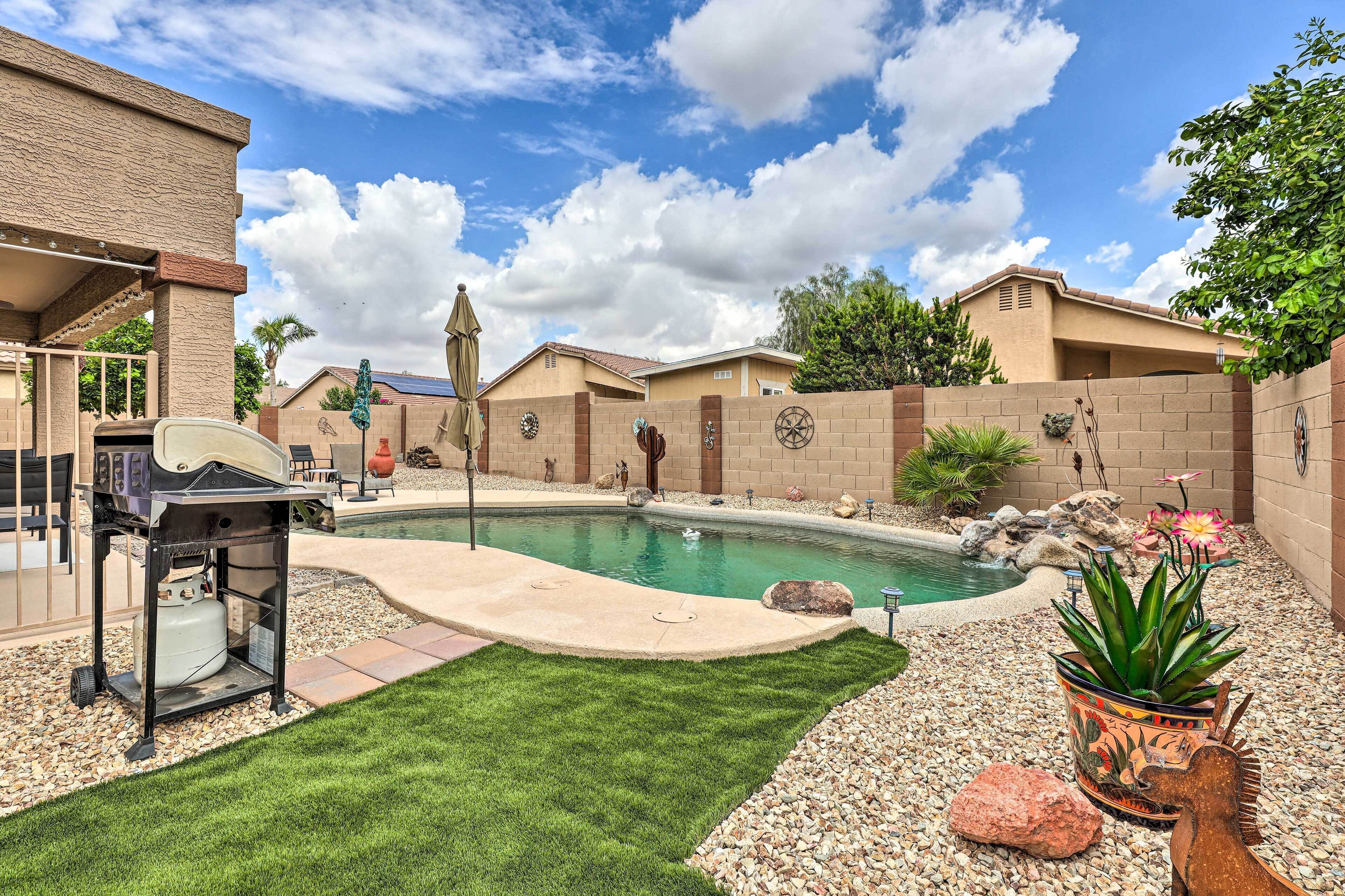 A backyard with a swimming pool, a barbecue grill, and a potted plant.