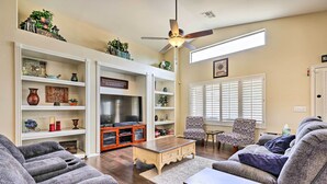 A living room with a flat-screen TV, a ceiling fan, and a fireplace. - Bbq-ready Oasis Near Golfing + Surprise Stadium! (Surprise)