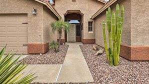 A two-story house with a garage, a pathway leading to the entrance, and a cactus in the front yard. - Bbq-ready Oasis Near Golfing + Surprise Stadium! (Surprise)
