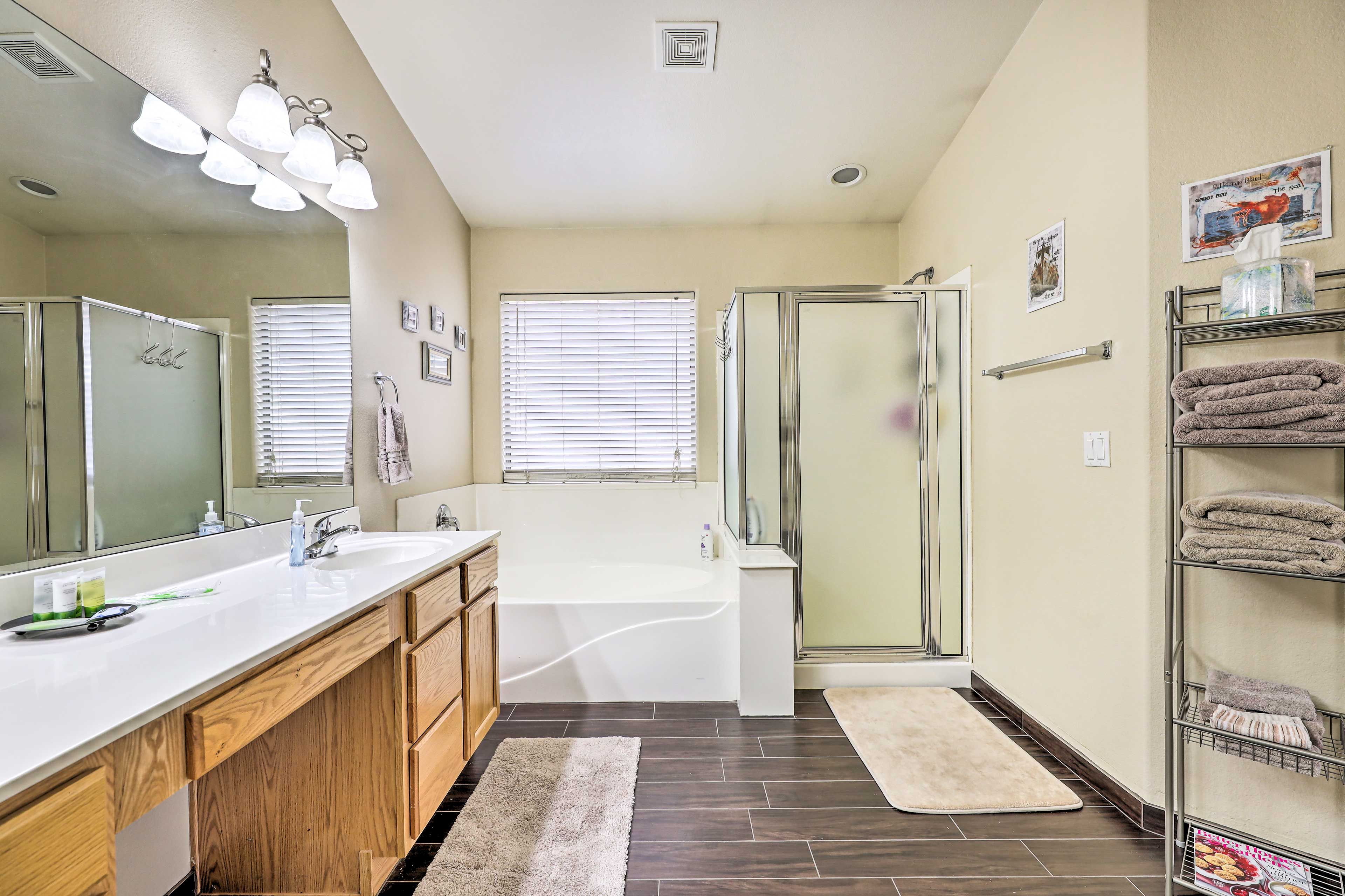 A modern bathroom with a double sink vanity, a large mirror, a bathtub, and a shower enclosure.