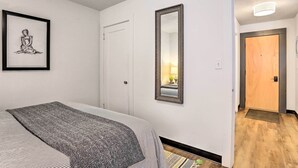 A bedroom with a bed, a framed artwork, a mirror, and a door leading to another room. - Beauty in the Black Hills: An Upscale Apt. in Lead (Lead)