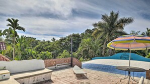 A rooftop pool area with a colorful umbrella, a lounge chair, and a seating bench. - Sayulita Condo: Walk to Beach, Plaza & Dining! (Sayulita)