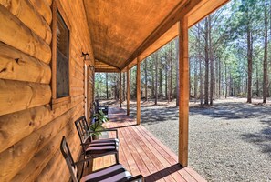 A wooden cabin with a covered porch, a bench, and a view of a forest. - 'the Breeze' - Broken Bow Cabin w/ Hot Tub & Deck! (Broken Bow)