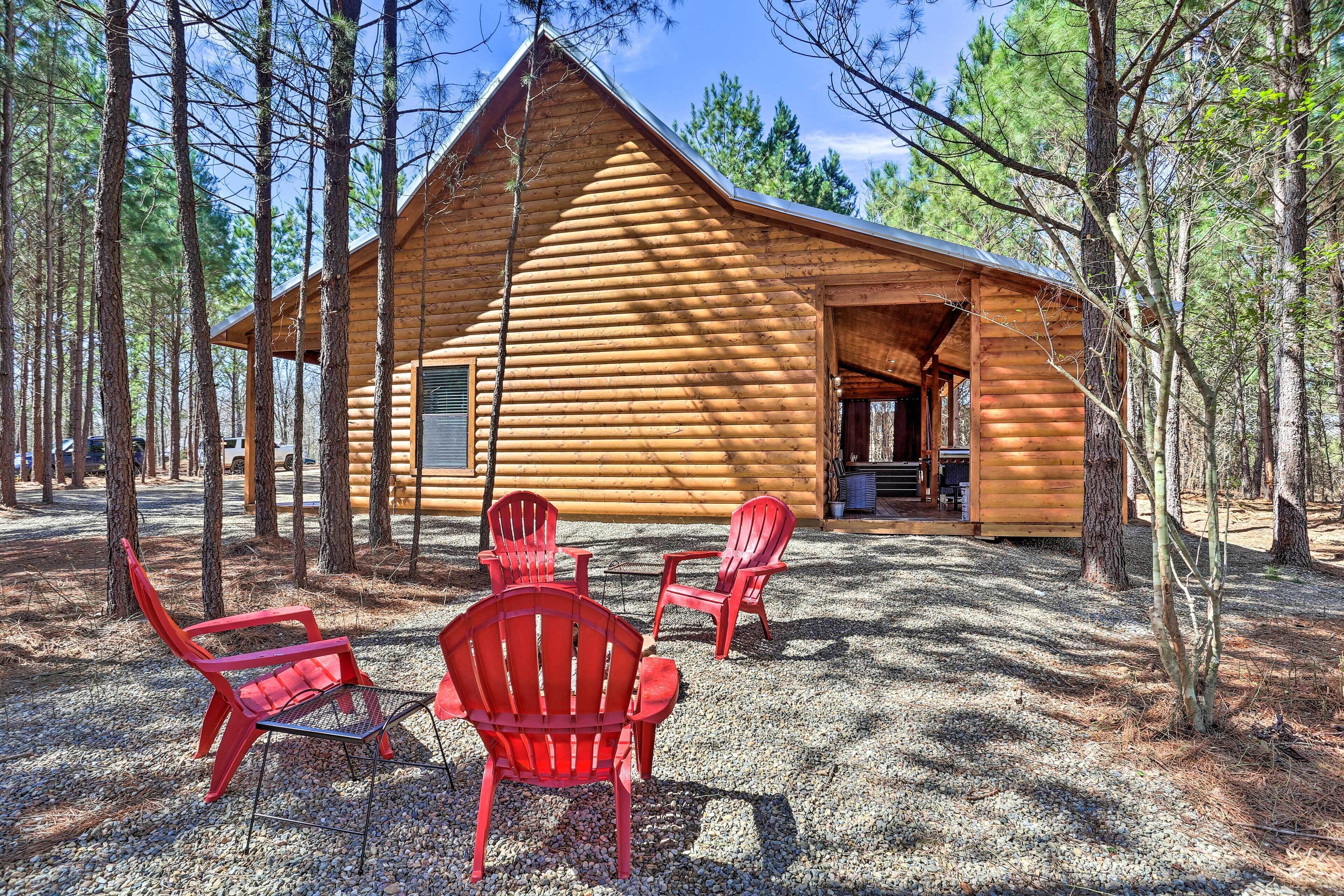 Una cabaña de troncos con un porche y tres sillas Adirondack rojas.