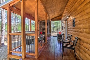 A wooden cabin with a covered porch, stone fireplace, and outdoor seating area. - 'the Breeze' - Broken Bow Cabin w/ Hot Tub & Deck! (Broken Bow)